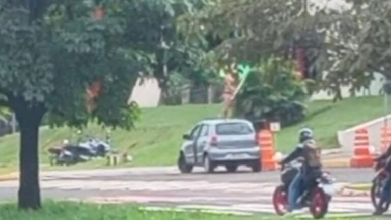 Mulher em protesto ousado clama por justiça fraternal sobre carro em Campo Grande, MS, gerando comoção.